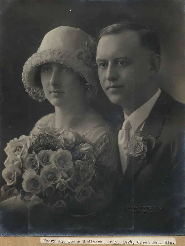 Black-and-white studio wedding portrait of a woman with a bouquet beside a man in a suit.
