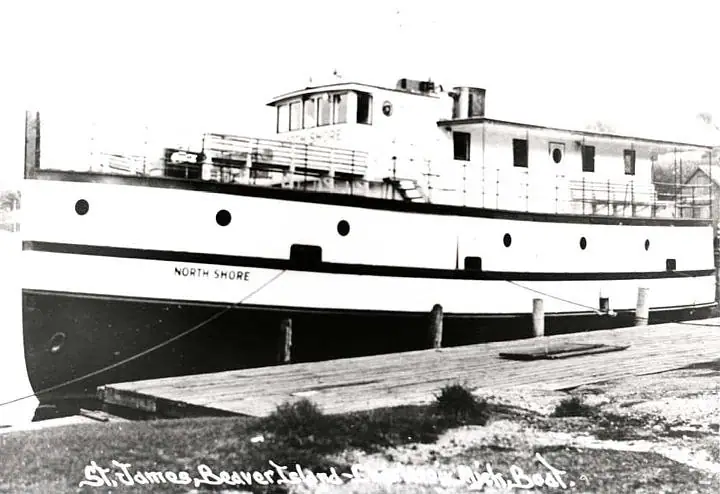 A large white workboat named North Shore moored beside a wooden pier.