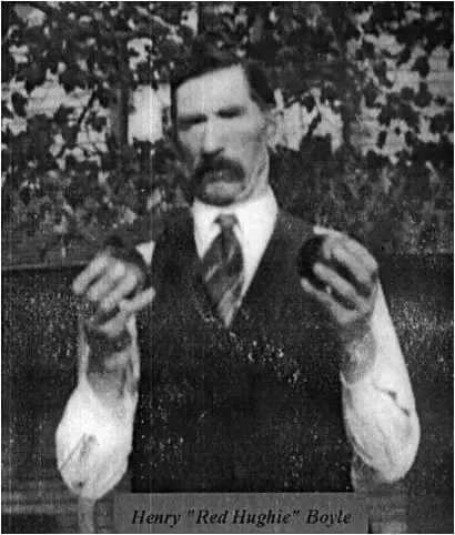 Black-and-white portrait of a mustached man holding two rounded objects, with a printed label below.