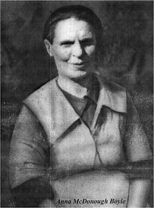 Black-and-white portrait of a woman in a collared jacket with her arms folded, against a dark background.