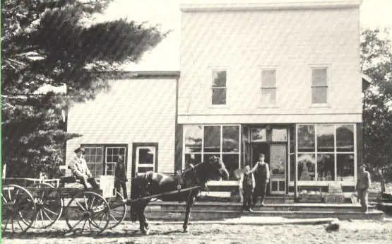 A horse-drawn wagon and several people stand outside a two-story storefront.