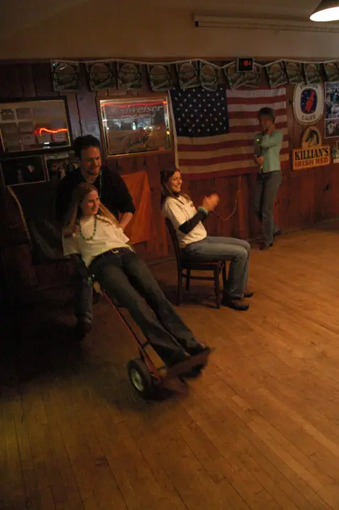 Four people gather in a wood-paneled room with beer advertisements and an American flag.