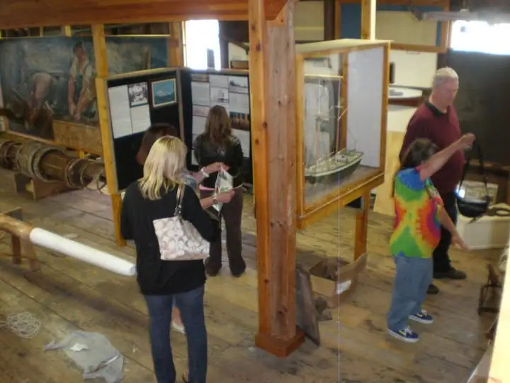 Visitors view maritime exhibits inside a wood-framed museum.
