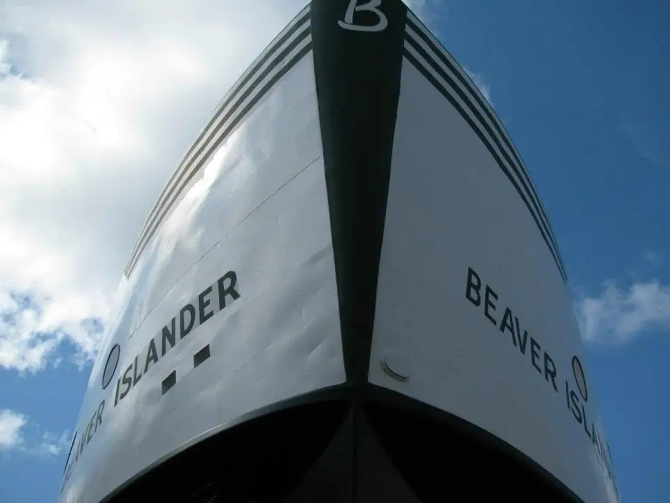 Close-up view of a ferry bow with lettering against a partly cloudy sky.