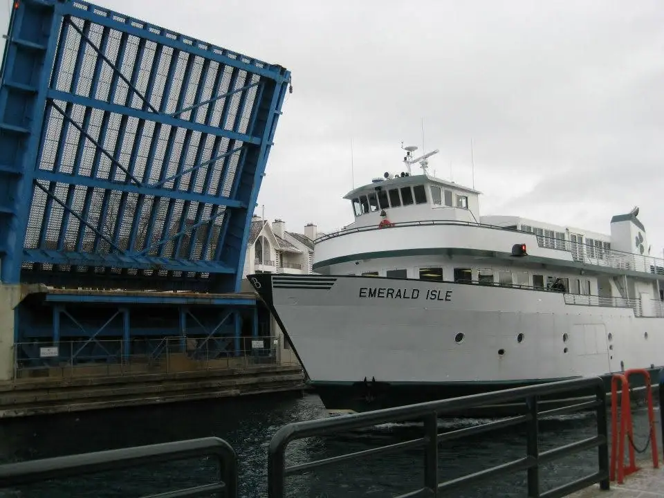 A white passenger ferry marked EMERALD ISLE sits beside a raised blue steel structure.