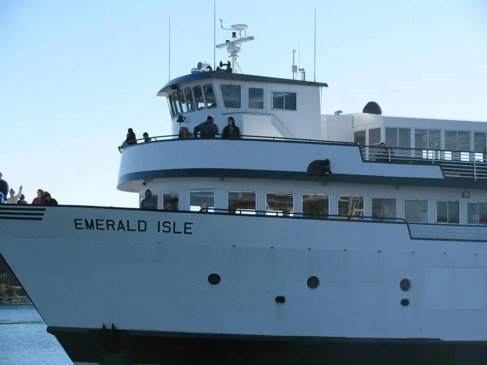 A white passenger ferry with people on its decks and its name printed on the hull.