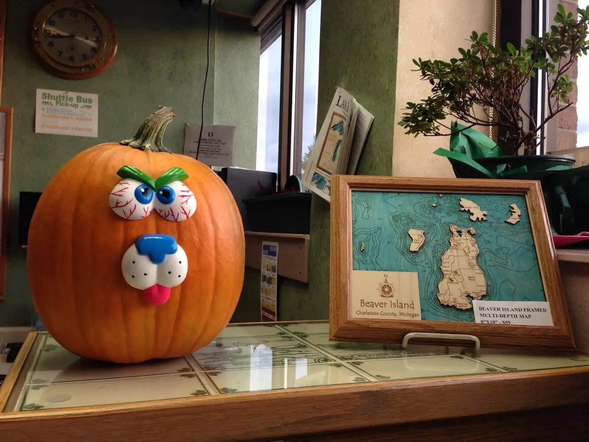 A decorated pumpkin sits beside a framed map on a counter in an office or reception area.