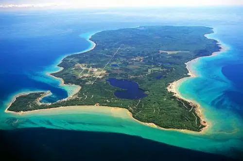 Aerial photograph of a forested landmass with beaches, roads, settlement, and inland water.