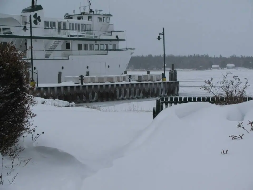 A white ferry sits beside a snow-covered pier in winter.