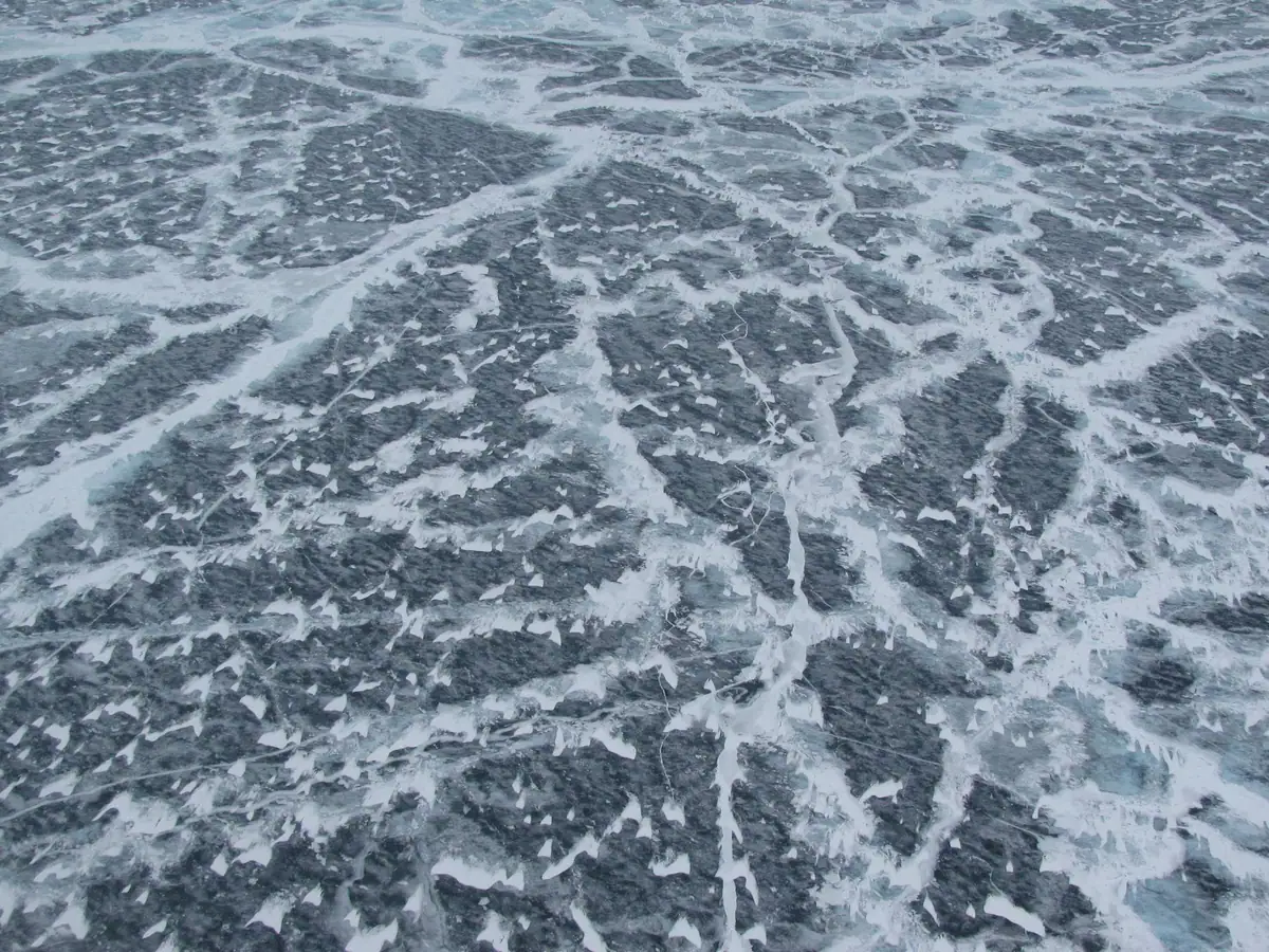 A textured expanse of broken ice with pale channels and scattered patches of dark water.