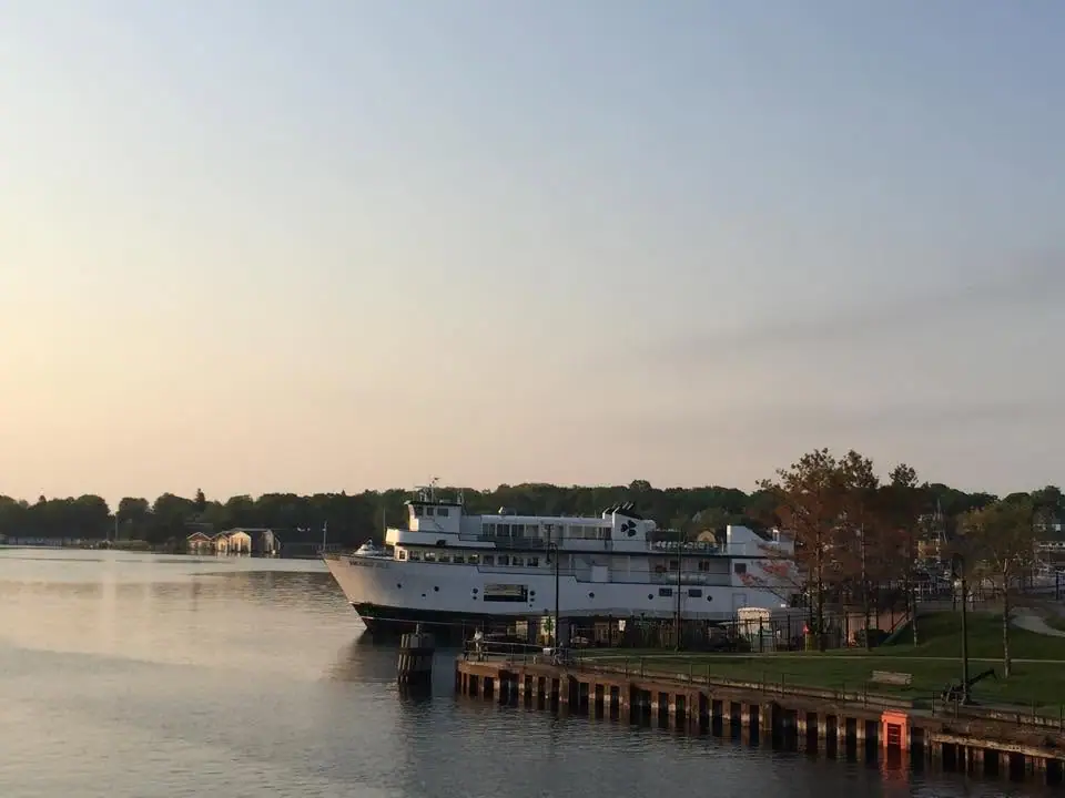 A large white ferry is moored beside a waterfront pier in warm low-angle light.