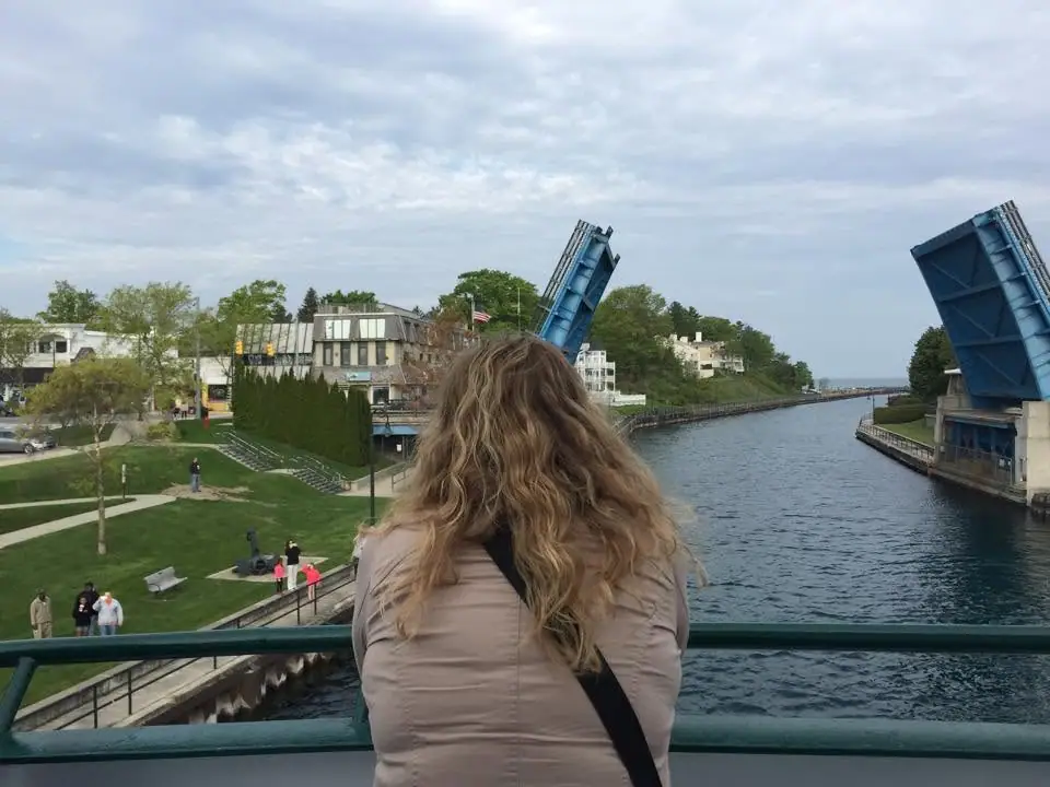 A person views a raised drawbridge over a waterway from a pedestrian bridge.