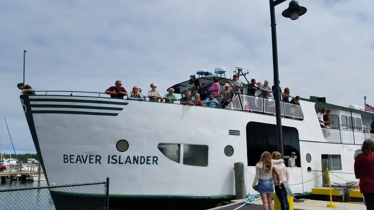 A white passenger ferry crowded with people is moored beside a dock in a marina.