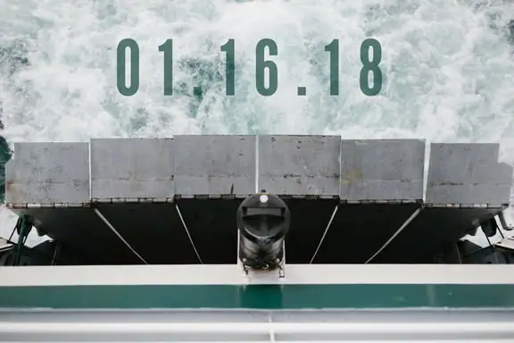 Close view of a vessel’s gray segmented structure, central fixture, and green-and-white railing.