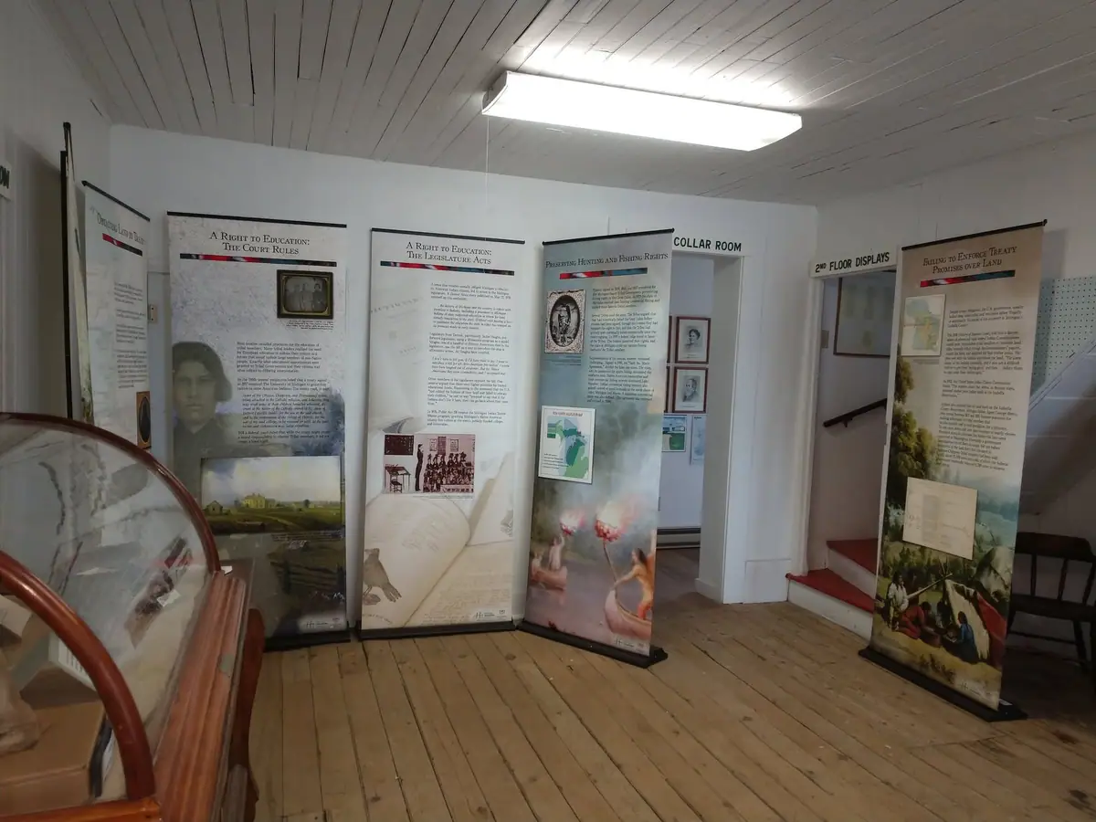 Interior exhibit room with freestanding panels about education, treaty enforcement, and hunting and fishing rights.