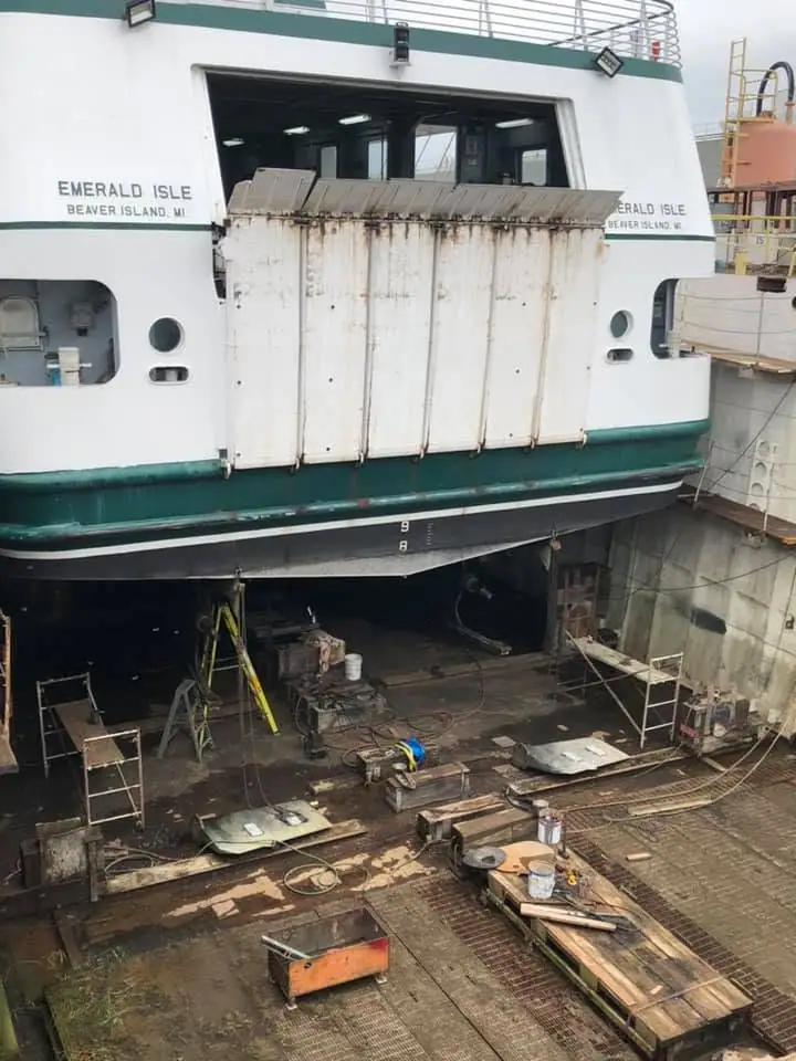 Passenger ferry suspended in a dry dock above maintenance equipment and tools.