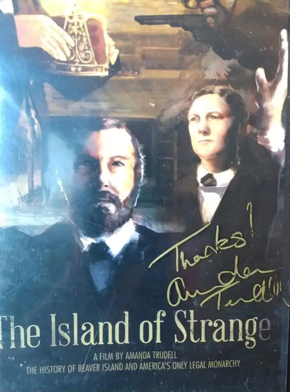 Photographed movie poster showing two formally dressed figures, a crown, a firearm, and printed and handwritten text.