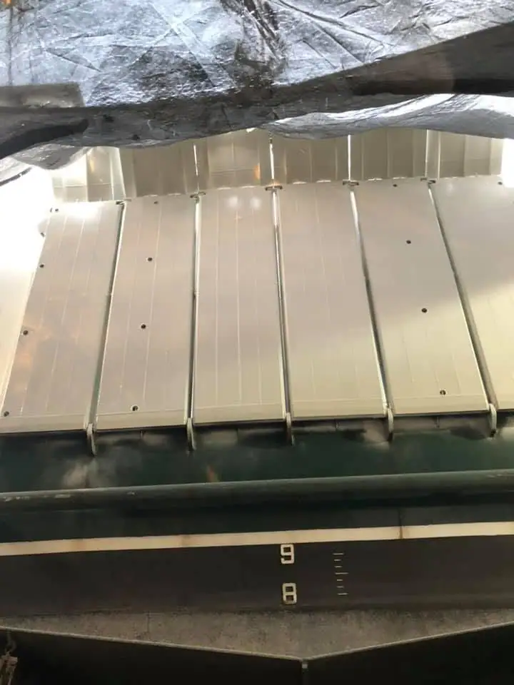 Close view of pale metal panels, dark beams, reflective insulation, and measurement markings inside a structure.
