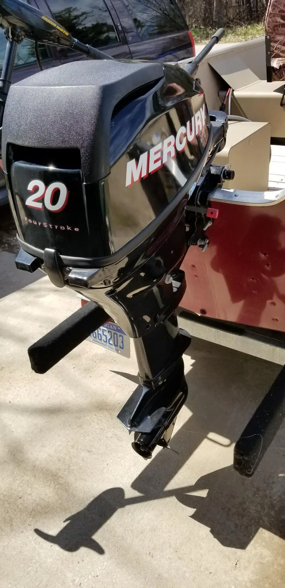 Close-up of a black Mercury outboard motor mounted on a small red-and-beige boat.