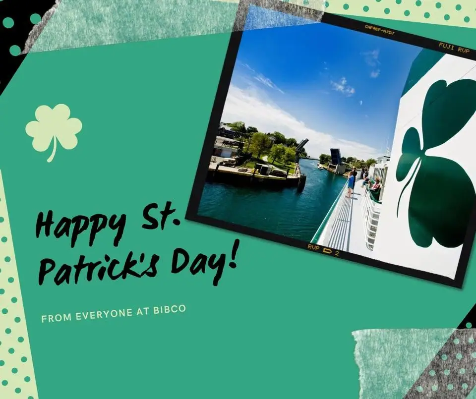 Green holiday greeting graphic with shamrocks and an inset waterfront photograph viewed from a passenger vessel.