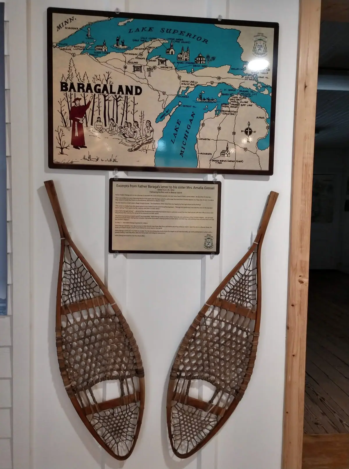 A wall display features an illustrated map, a text panel, and a pair of wooden snowshoes.