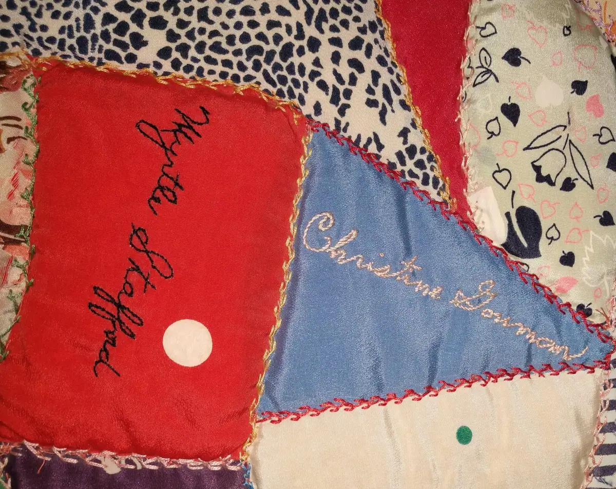 Close-up of colorful fabric patches with decorative stitching, patterns, dots, hearts, and embroidered cursive writing.