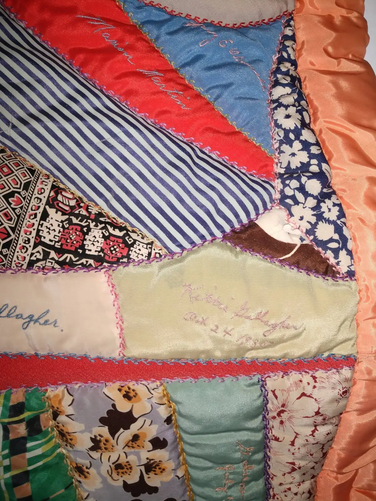 Close-up of a colorful patchwork quilt made from patterned fabrics with embroidered writing.