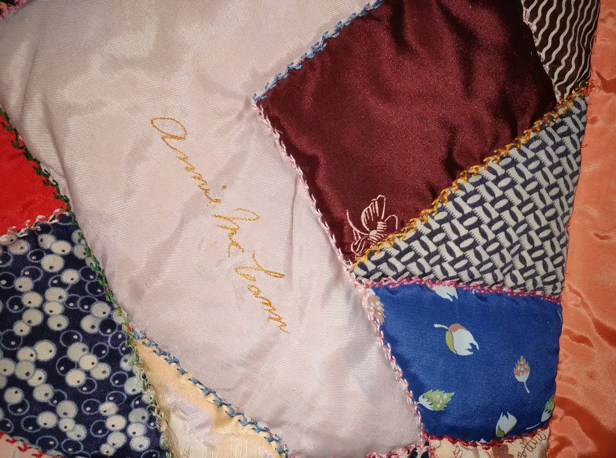 Close-up of a multicolored patchwork quilt with embroidered trim and gold cursive lettering.