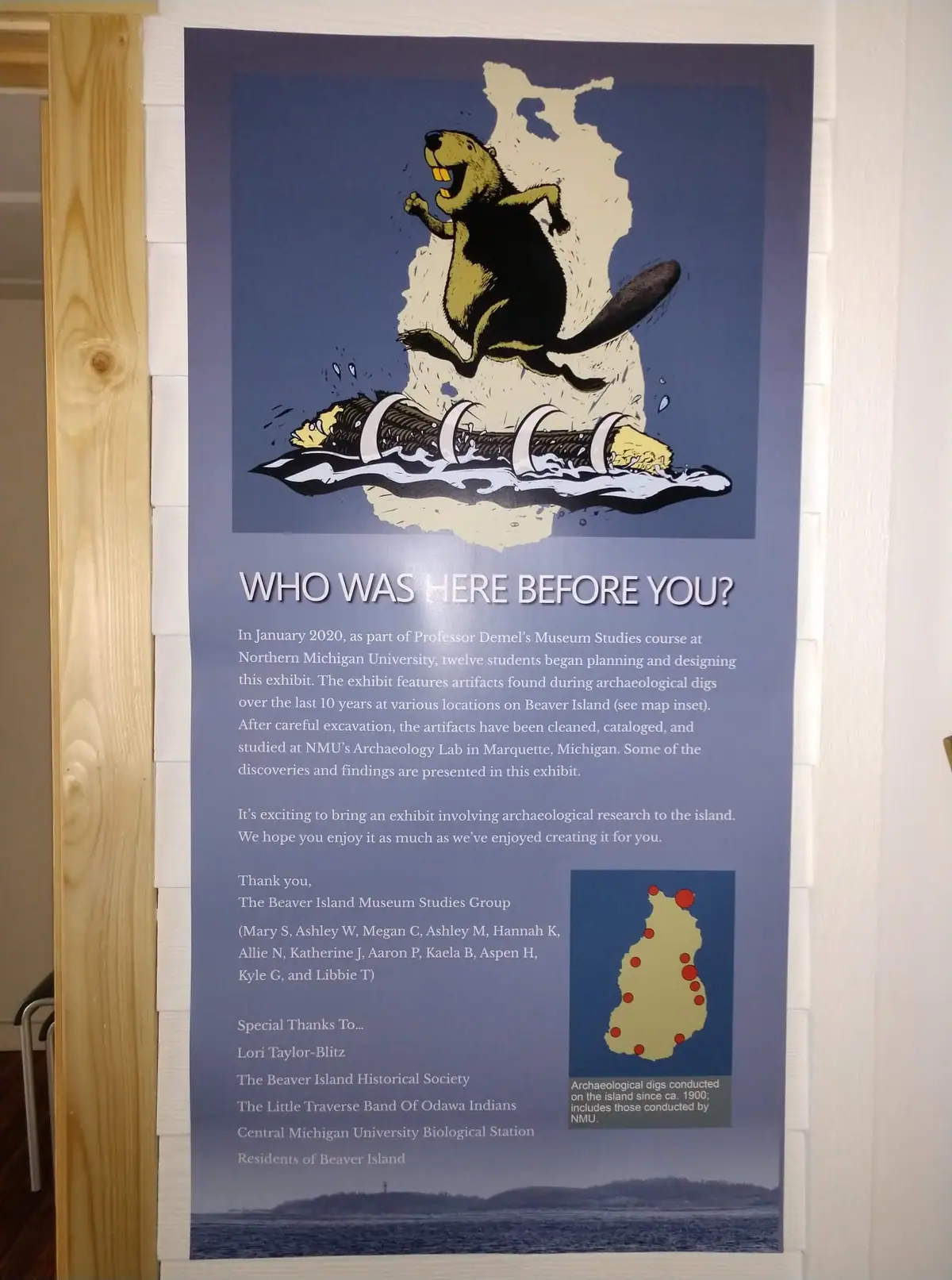 Photograph of an illustrated archaeology exhibition poster mounted on an interior wall.