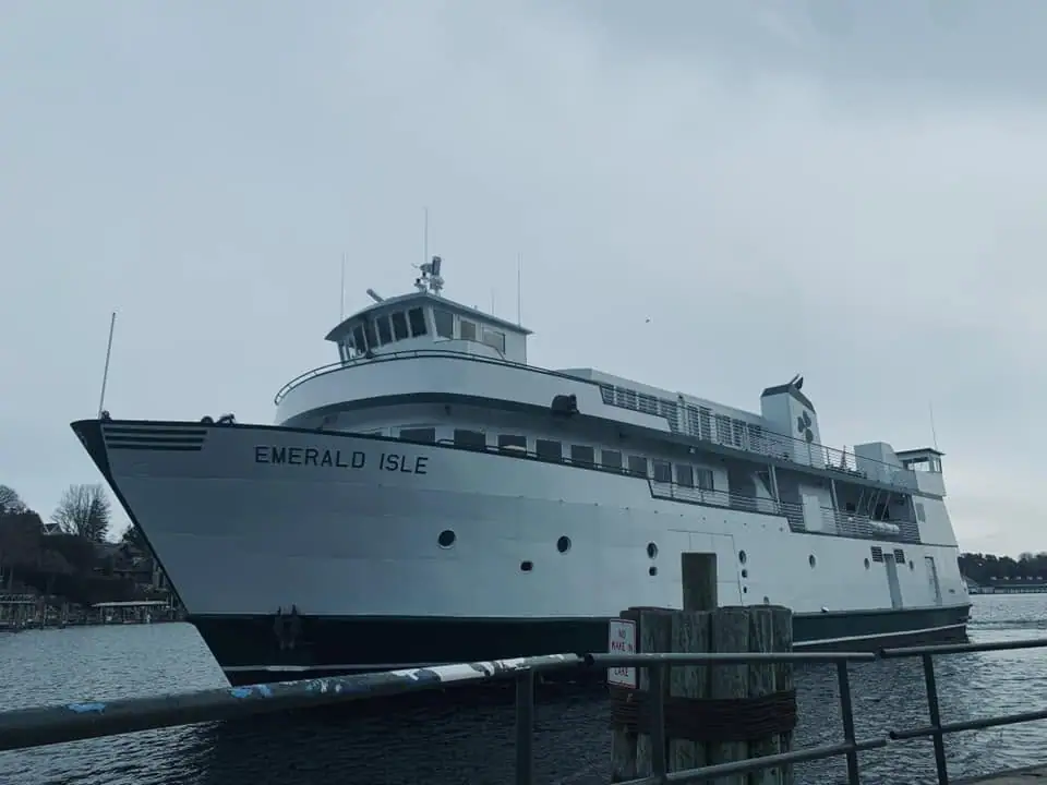 A white multi-deck ferry named EMERALD ISLE sits beside a pier under an overcast sky.