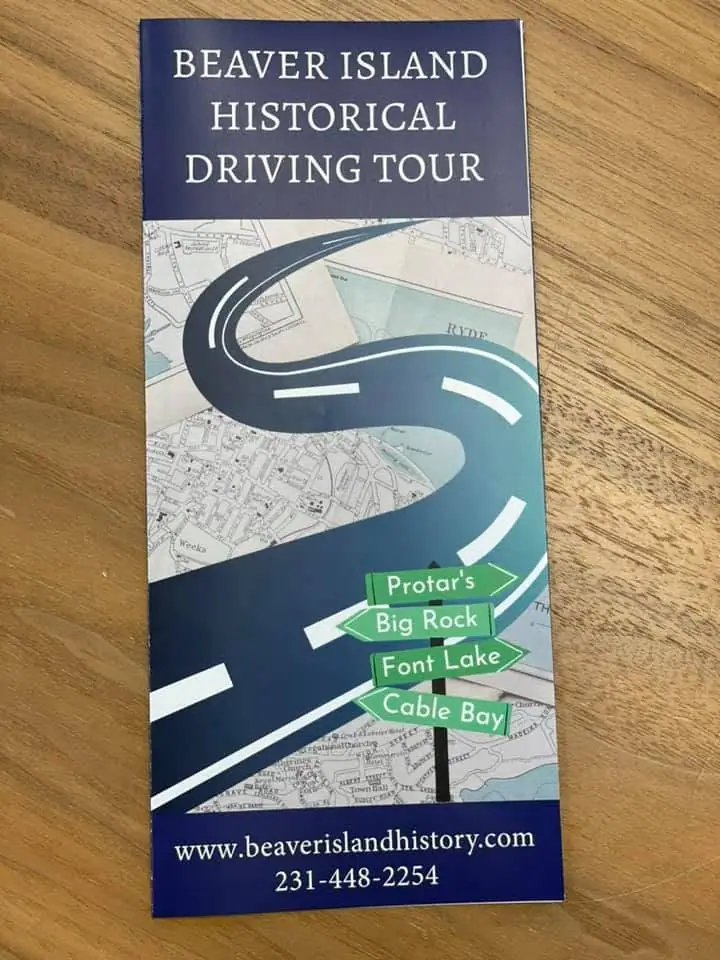 A driving-tour brochure with a stylized road over a map and four green directional signs.