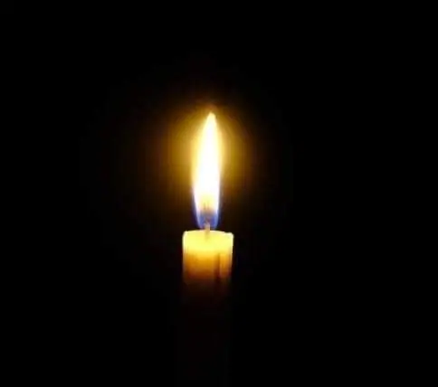 A single lit candle with a bright flame stands against a black background.