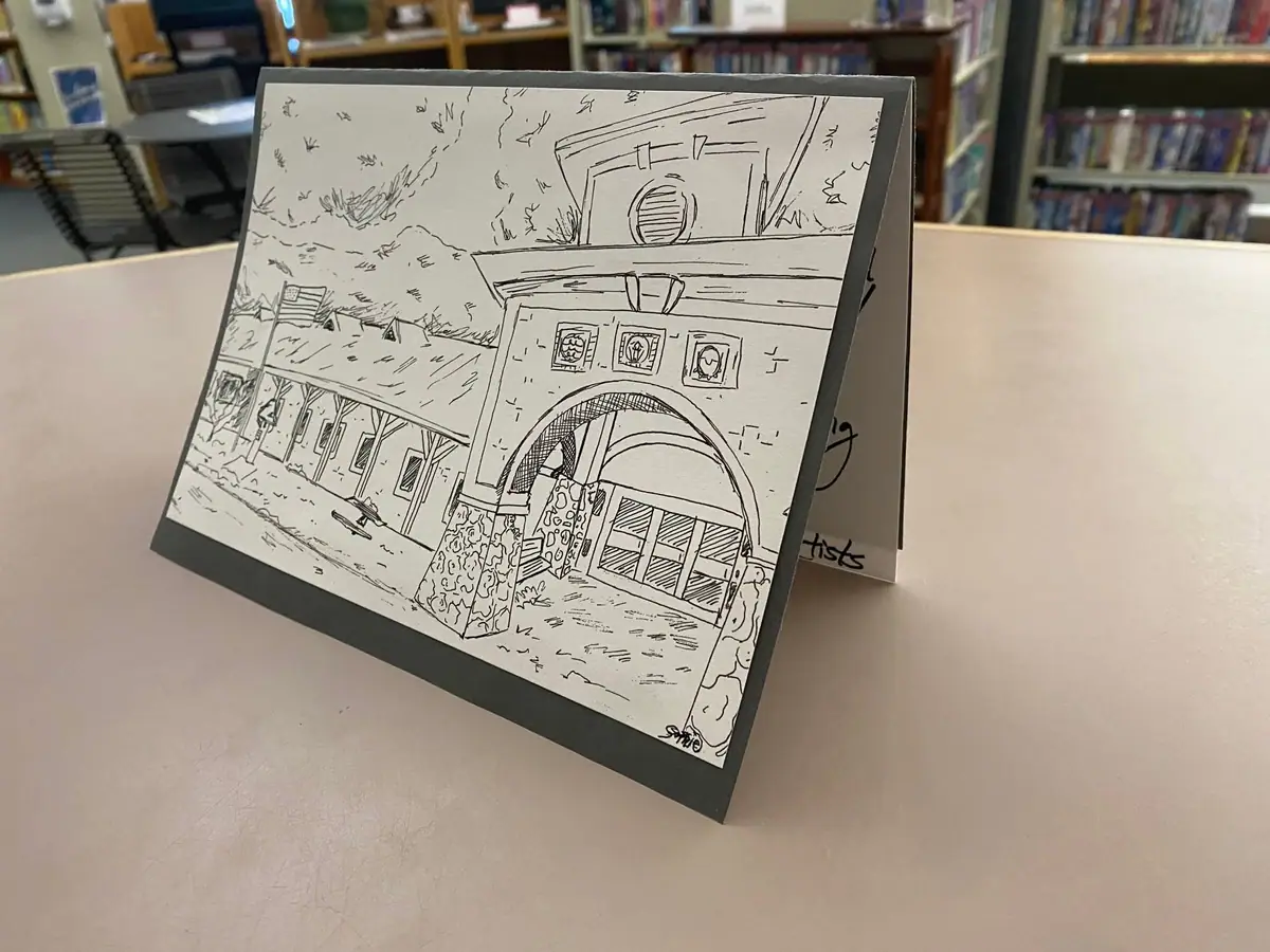 Photograph of a black-and-white architectural drawing displayed on a stand in front of library shelves.