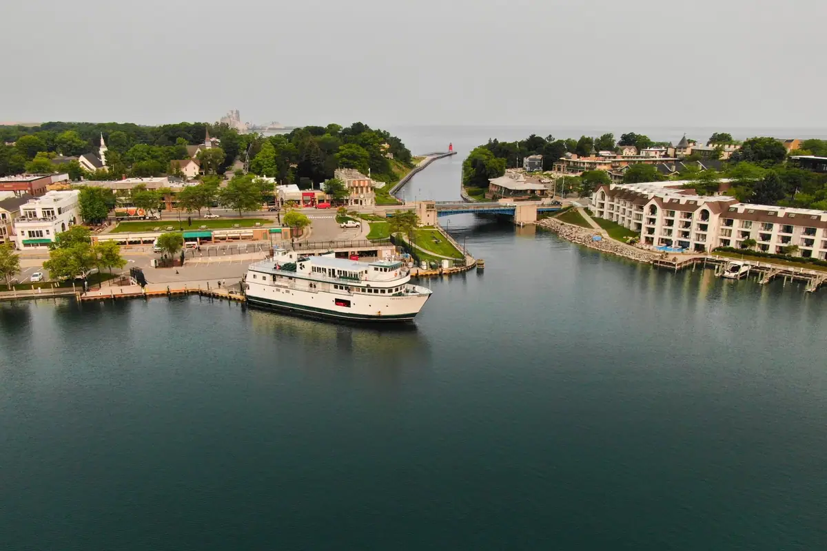 Aerial photograph of a passenger ferry docked in a harbor beside a bridge and waterfront buildings.