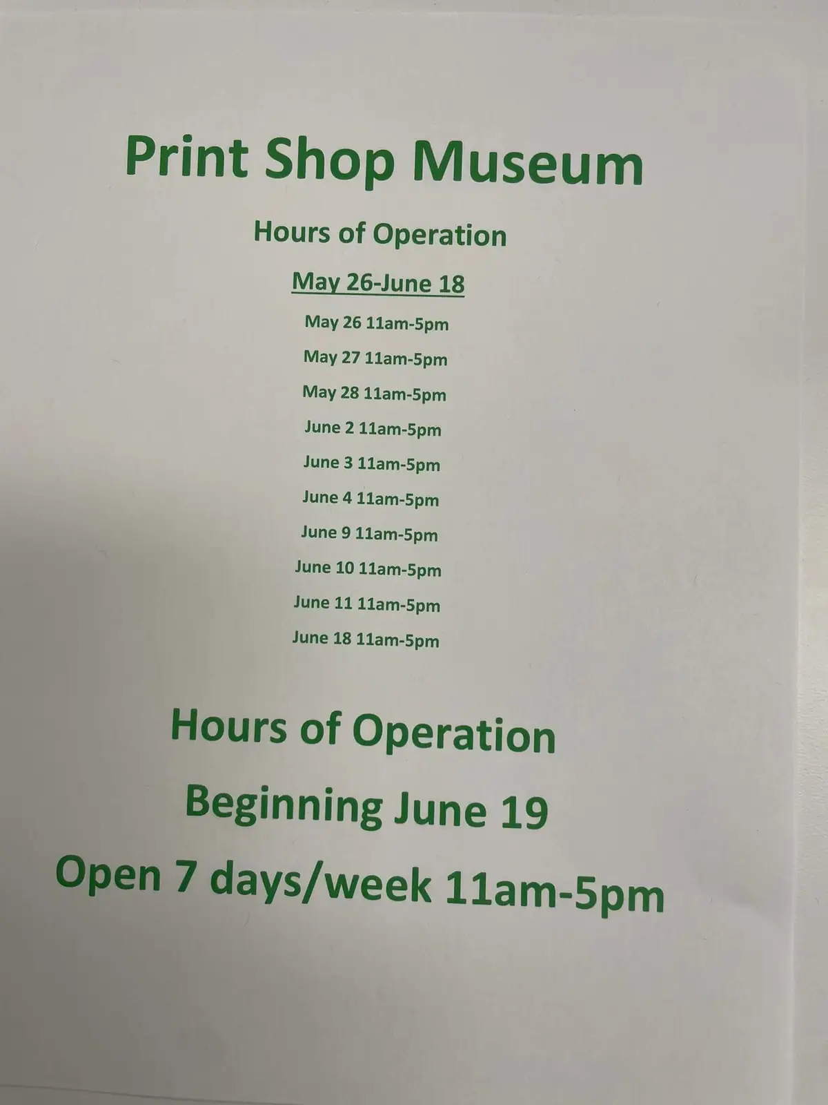 Photograph of a printed green-and-white hours-of-operation notice for a print shop museum.