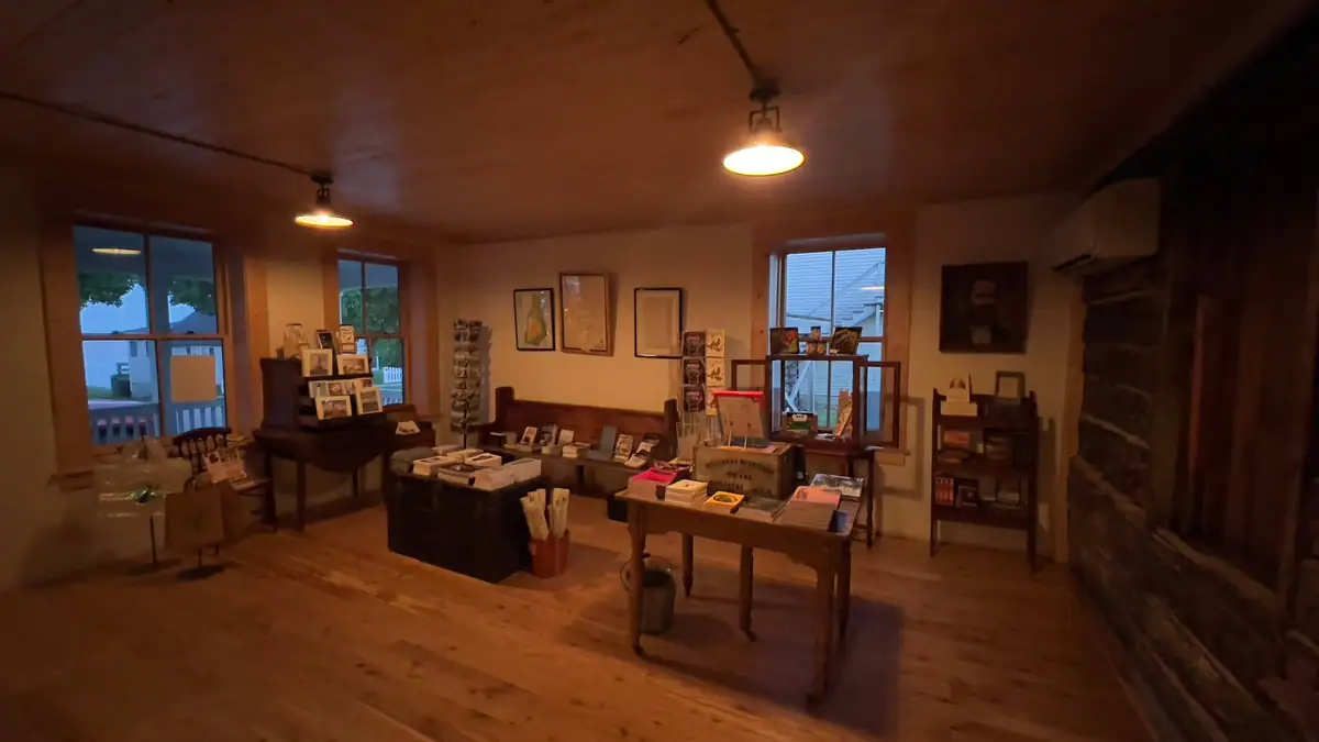 Wood-paneled interior with display tables, framed pictures, books, and a large stone fireplace.
