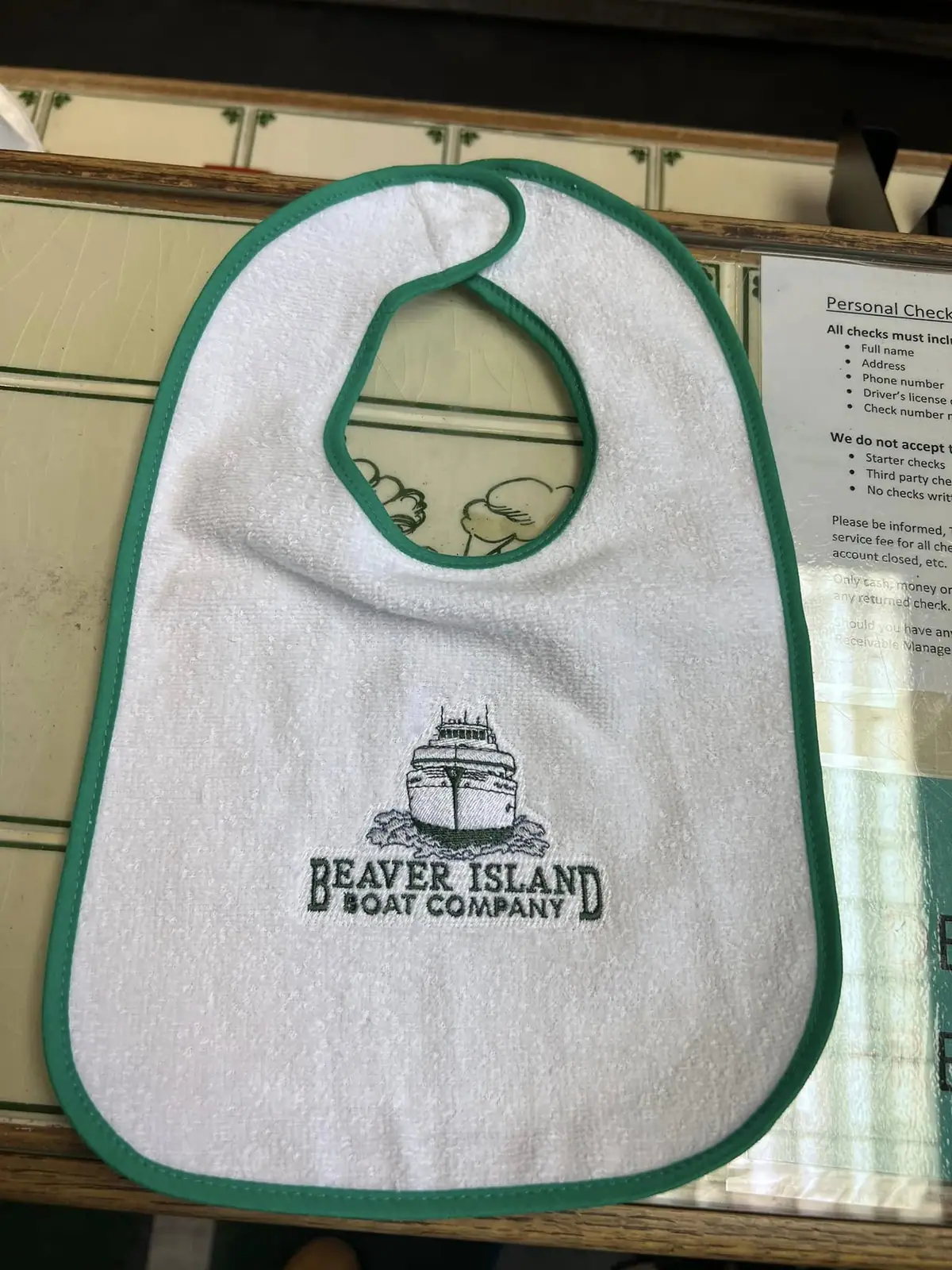 White bib with green edging and an embroidered passenger boat above the words “BEAVER ISLAND BOAT COMPANY.”