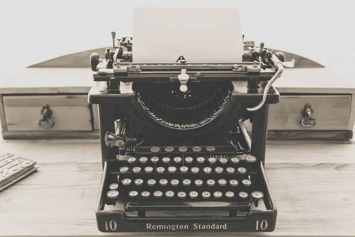 Vintage typewriter with blank paper on a wooden desk.