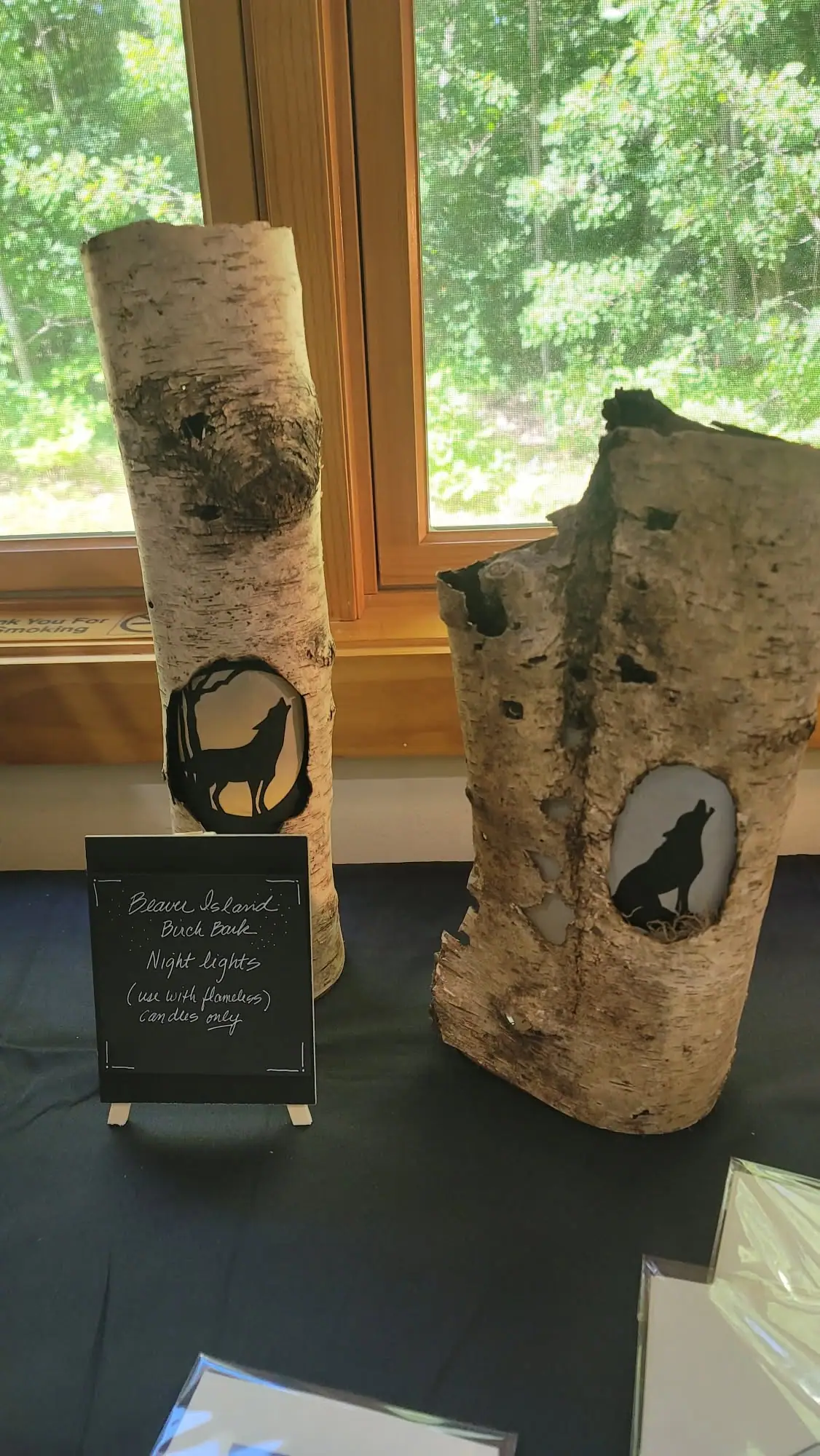 Two birch-bark night-light holders with animal silhouettes displayed in front of a window.