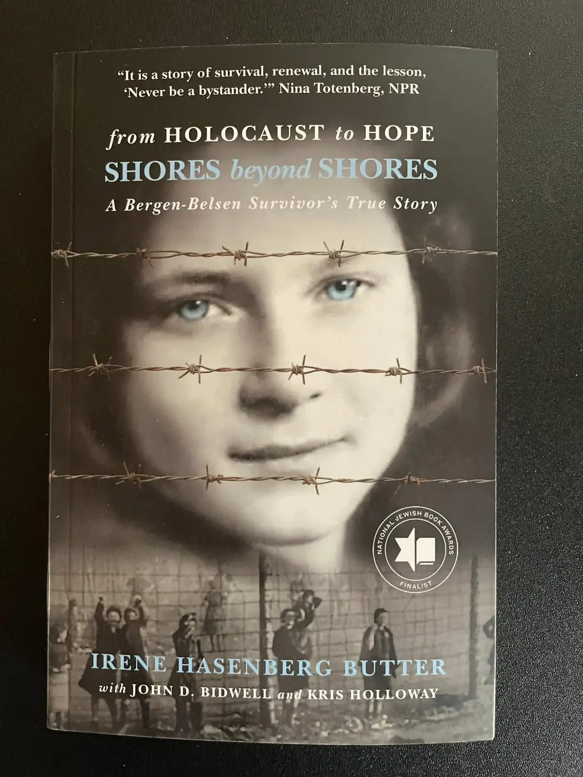 Photograph of a book cover showing a child's face behind barbed wire and a circular award seal.