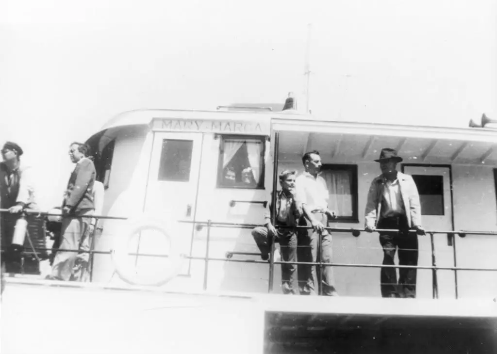Black-and-white photograph of several people standing on the deck of a vessel marked “MARY-MARGARITA.”