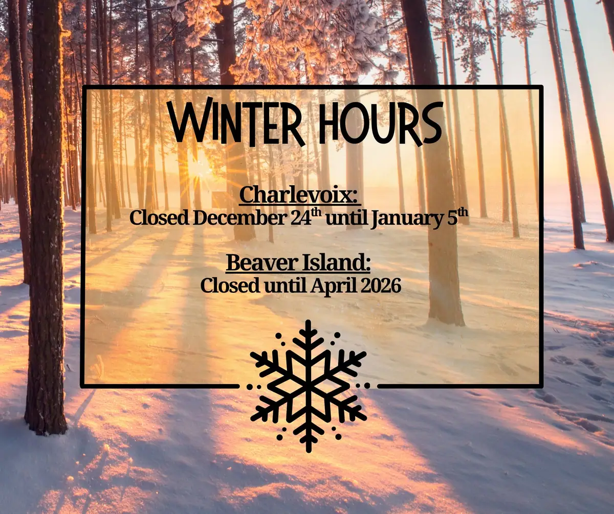A winter-hours notice overlays a sunlit, snow-covered pine forest with a large black snowflake graphic.