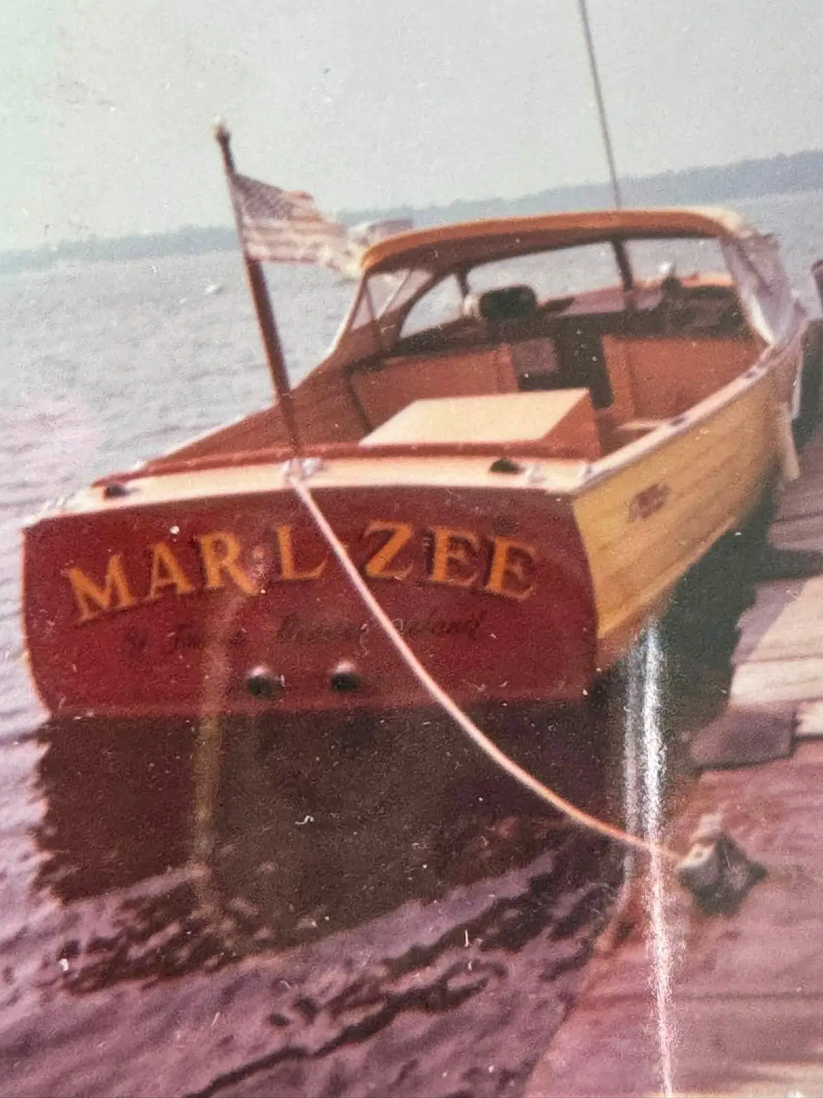 Small wooden motorboat named MARLZEE moored beside a wooden dock.