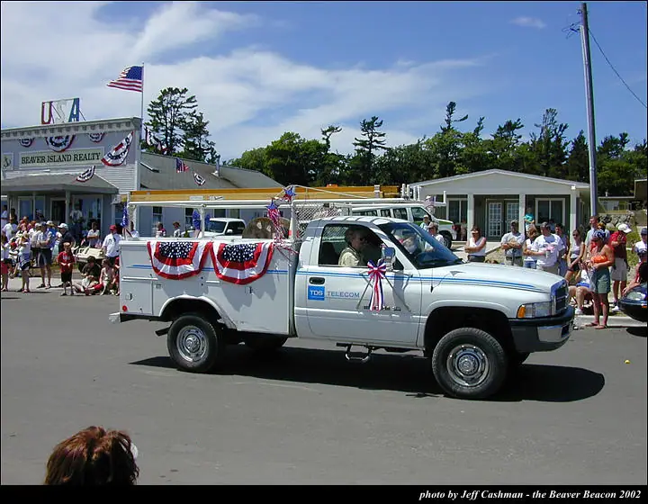 A decorated utility truck passes spectators during a parade.
