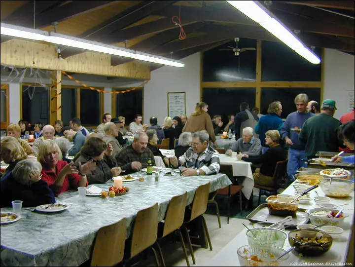 Crowded hall with adults seated at long tables beside a buffet.