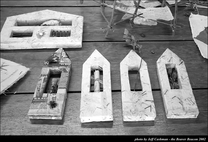 Black-and-white photograph of handmade paper-covered forms arranged on wooden planks.