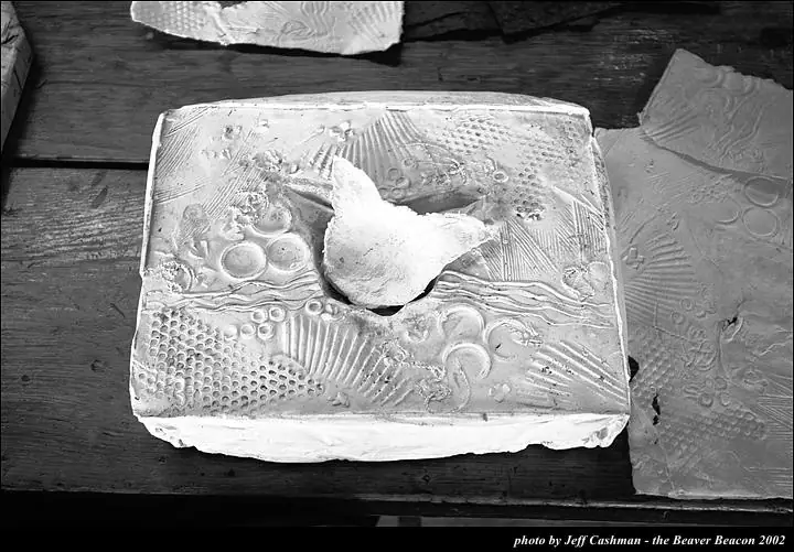 Black-and-white photograph of textured paper sculptures arranged on a wooden tabletop.