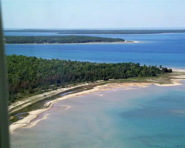 Aerial view of blue water, wooded shorelines, and pale sandbars.