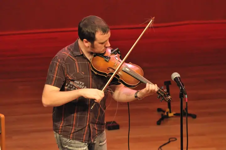 A violinist performs onstage beside a microphone.