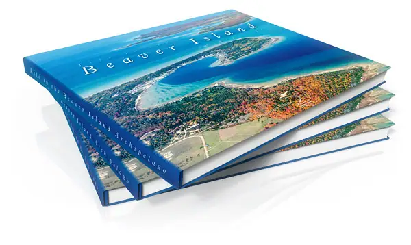 Stacked blue hardcover books with an aerial coastal photograph and white title lettering on the top cover.